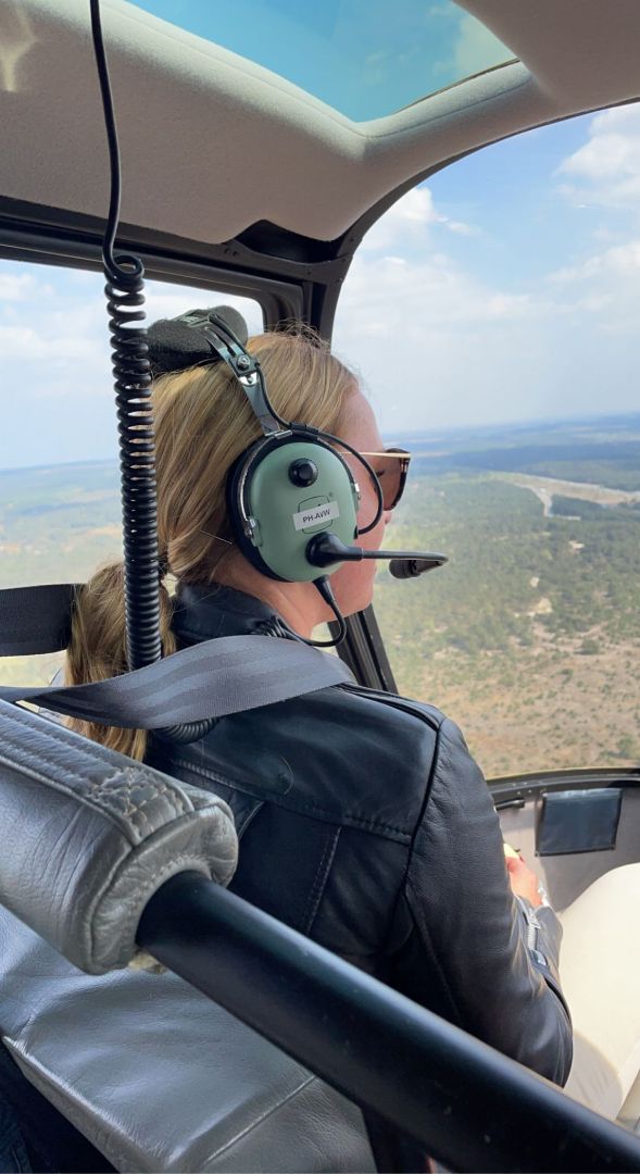 Medewerker van Microtechniek tijdens helikoptervlucht bij bedrijfsuitje, onderdeel van een betrokken team in precisietechniek en machinebouw